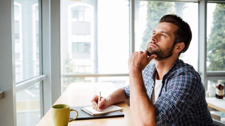 Foto de un hombre pensando y mirando hacia arriba mientras toma un café, supuestamente buscando su qué oficina Lanbide le corresponde.