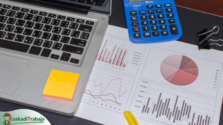 Foto de una mesa de trabajo con un portátil y gráficos impresos en referencia a las ofertas de empleo de Lanbide sobre administración y oficinas.